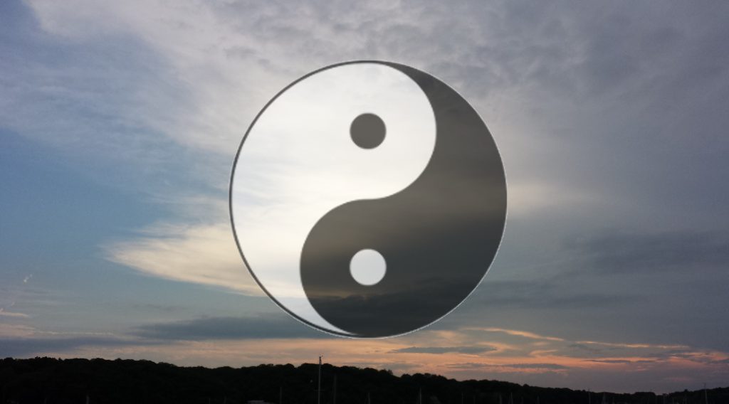 Yin-yang symbol over a cloudy sunset sky