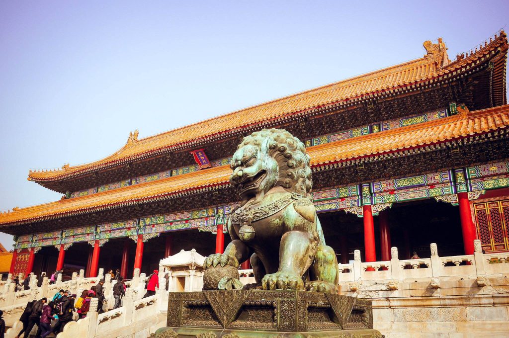Guardian lion statue in front of a traditional Chinese palace hall